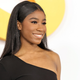 Lyric Ross wears a one-shoulder black dress at a red-carpet event.